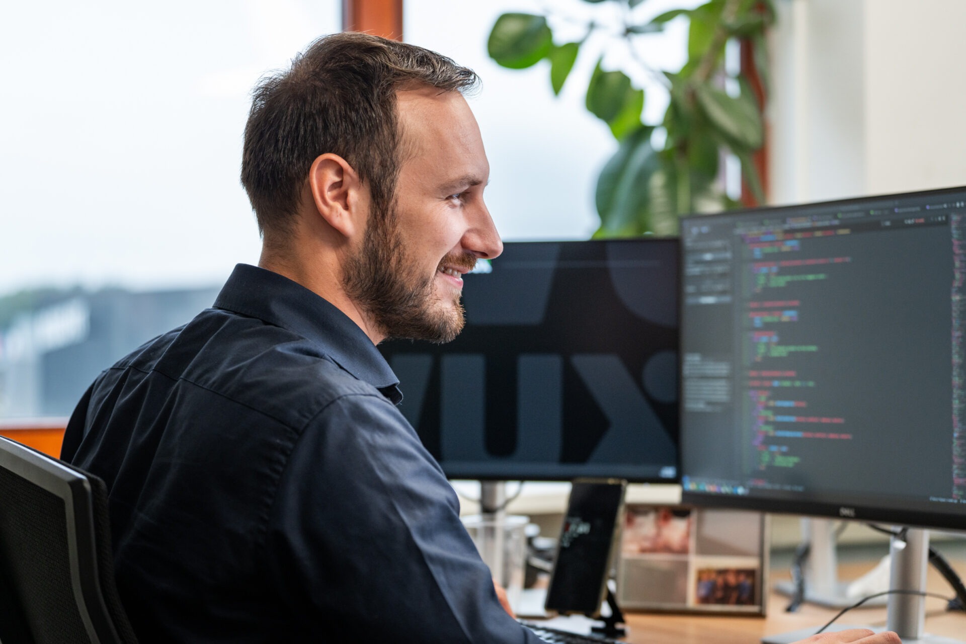 Een IT-specialist van Wux AI werkt achter een monitor aan de code en IT-architectuur om het rendement van AI-systemen te maximaliseren.