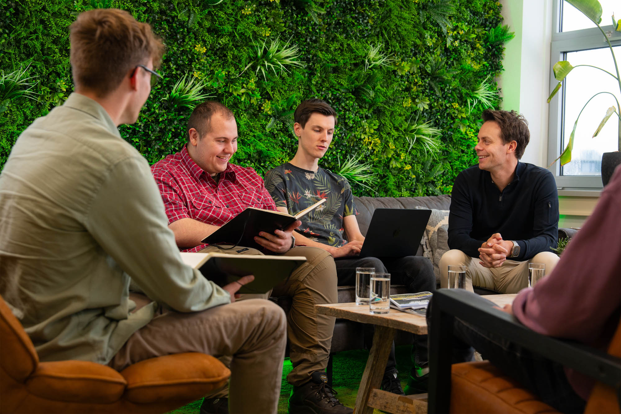 Een team zit in een informele kantoorsetting te overleggen over een AI-strategie om Shadow AI in kaart te brengen.