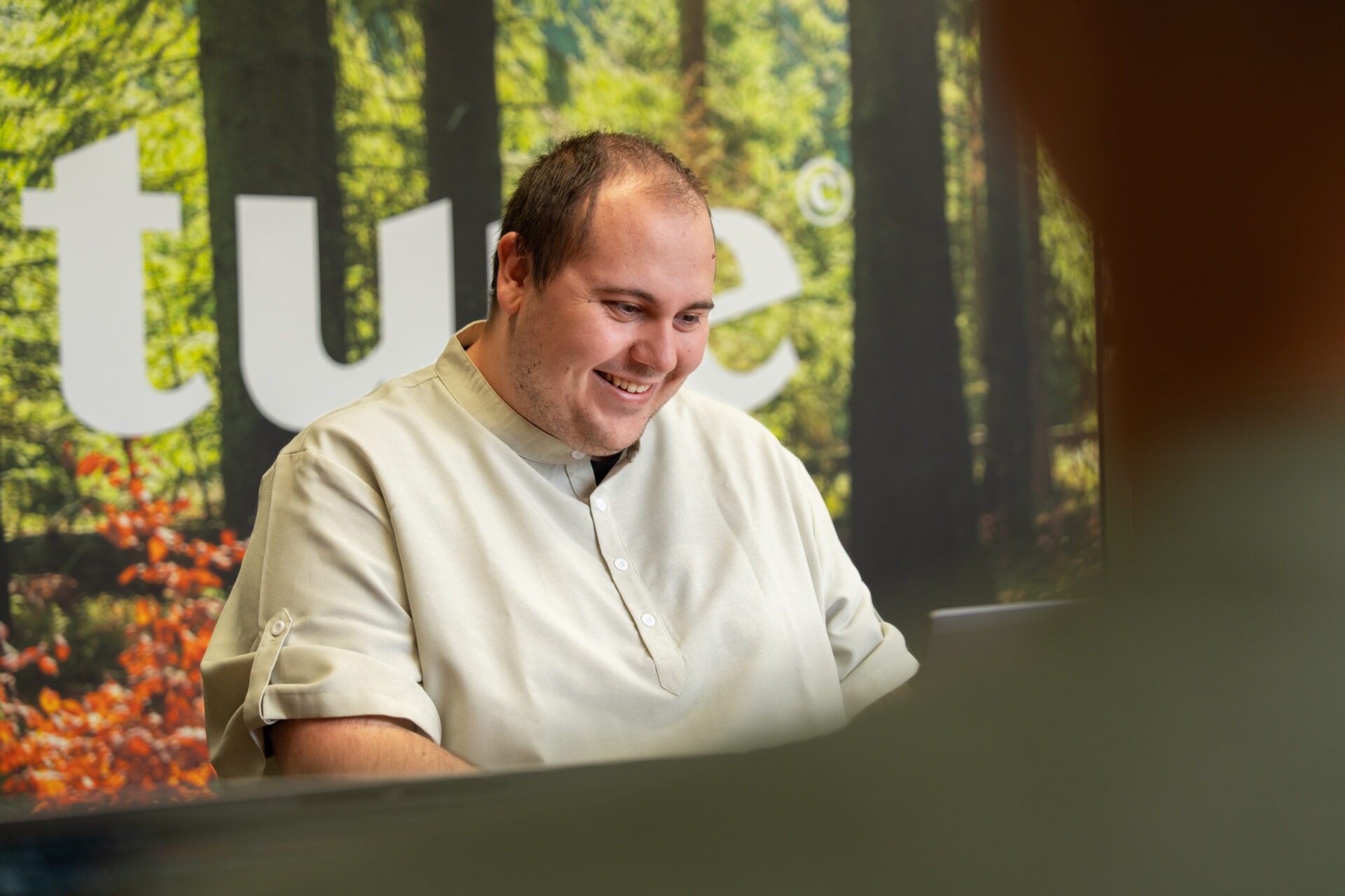 Een medewerker werkt glimlachend om de risico's van Shadow AI op de werkvloer te elimineren.