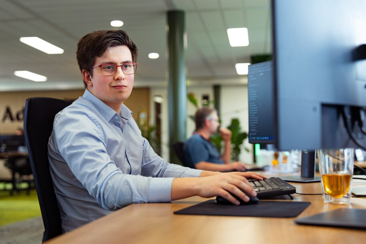 Medewerker van Wux AI werkt op kantoor achter een computer, ter illustratie van hoe AI-oplossingen de werkdruk verlagen.