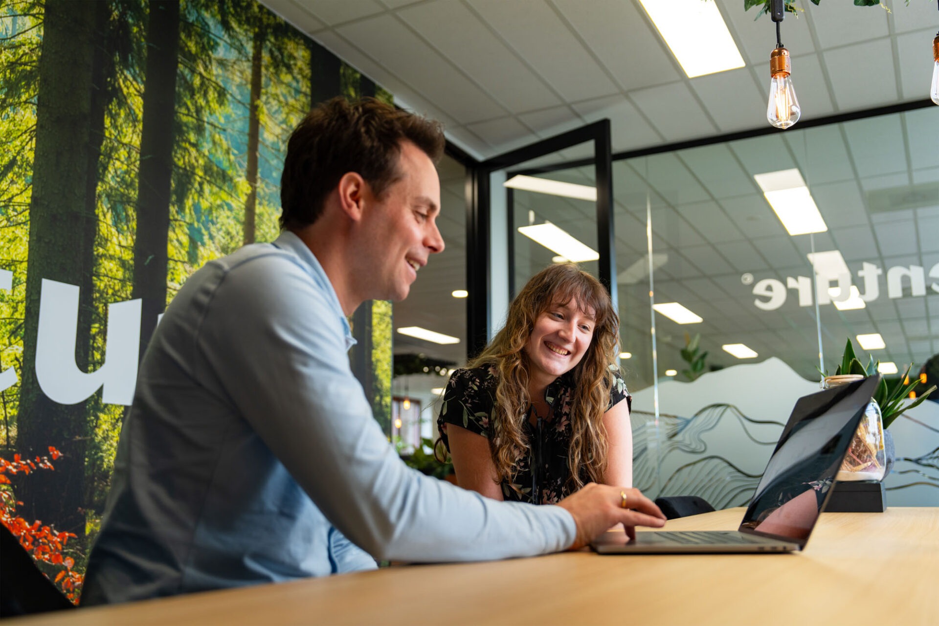 Een Wux AI-expert en een tevreden medewerker testen samen een gepersonaliseerde AI-assistent.